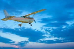 A small plane traveling through a blue sky with clouds on the way to New Shoreham, Block Island.