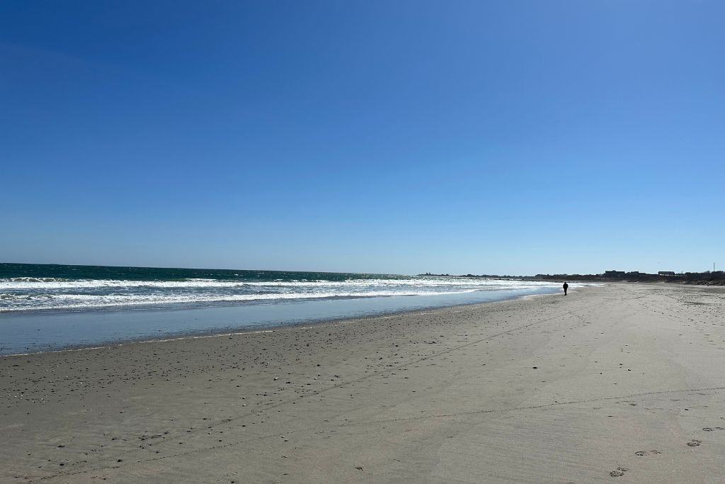 A lone walker strolling along the water's edge at Scarborough Beach State Park.