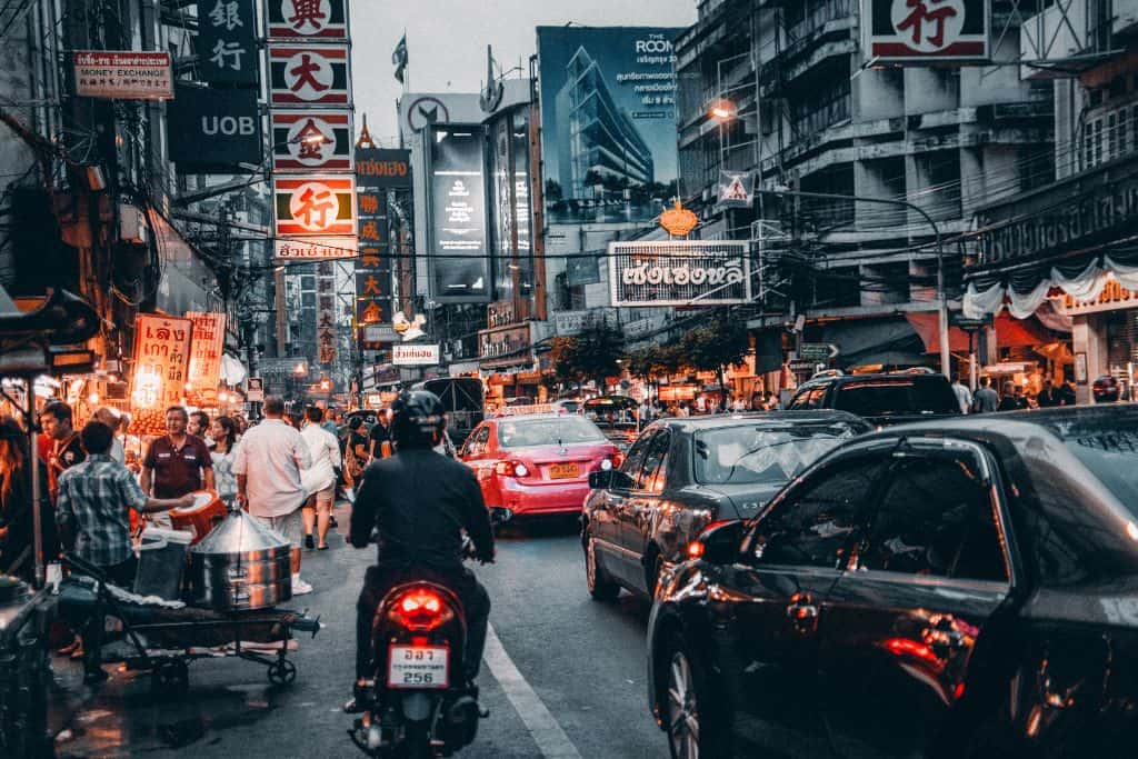 The busy congested streets of Bangkok with lots of cars, taxis, motorcycles, and people.