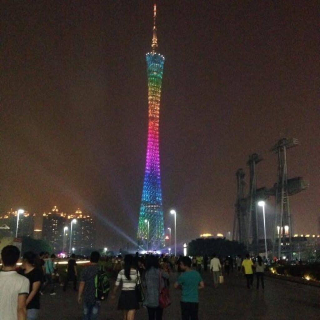 The brightly rainbow colored Canton Tower reaching upward into the dark night sky.