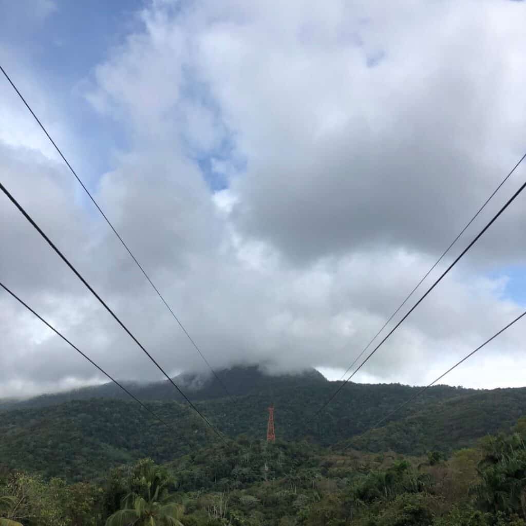 The cable car line rising up toward the mountain which is shrouded in cloud cover.