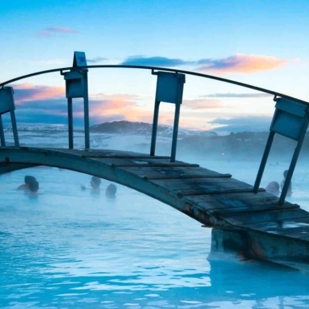 A curved bridge over the blue steaming waters of the Blue Lagoon.