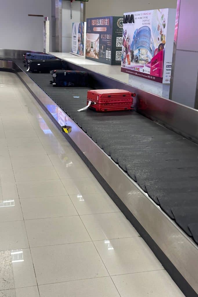 The luggage belt at KLIA with a red suitcase on it.