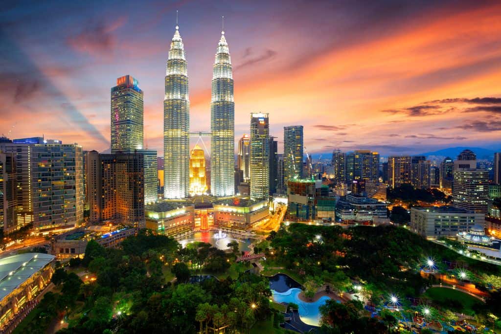 The Petronas Towers of the Kuala Lumpur skyline in an orange colored sunset.