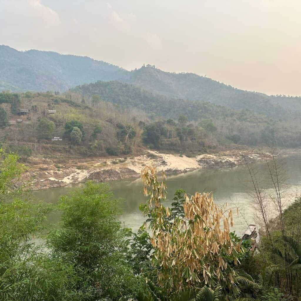 The slow moving Mekong River between high green misty hills on each side.