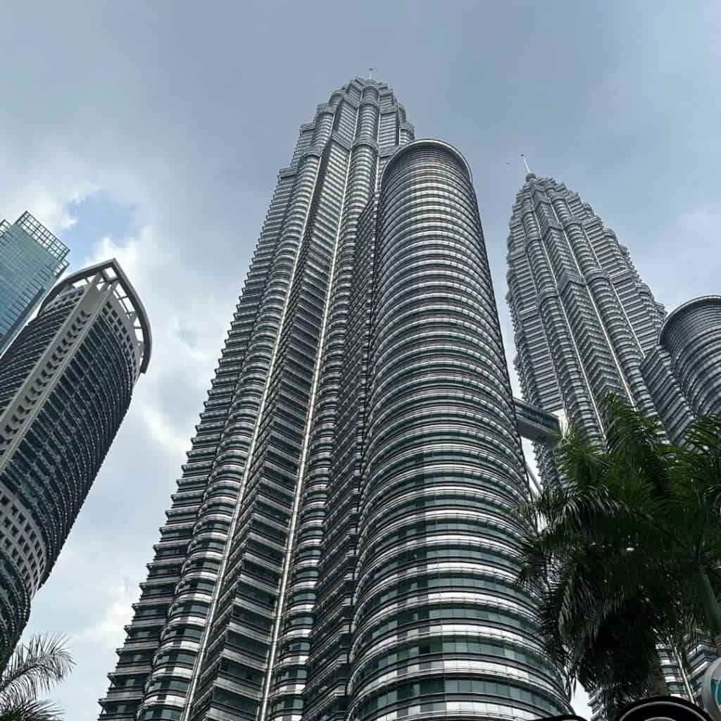 The silver Petronas Towers reaching toward a cloudy sky.