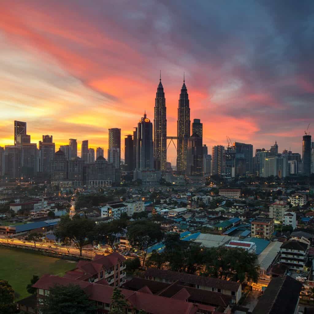 The skyline of Kuala Lumpur with the Towers standing out with the pink and orange setting sun behind it.