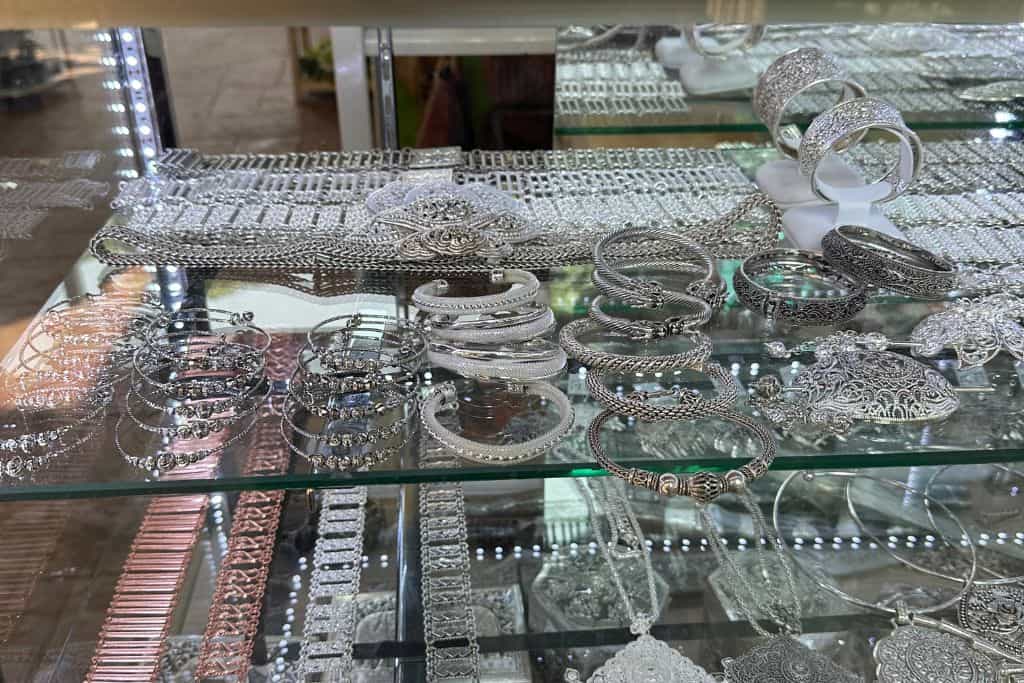 A glass case holding an assortment of silver jewelry for purchase.