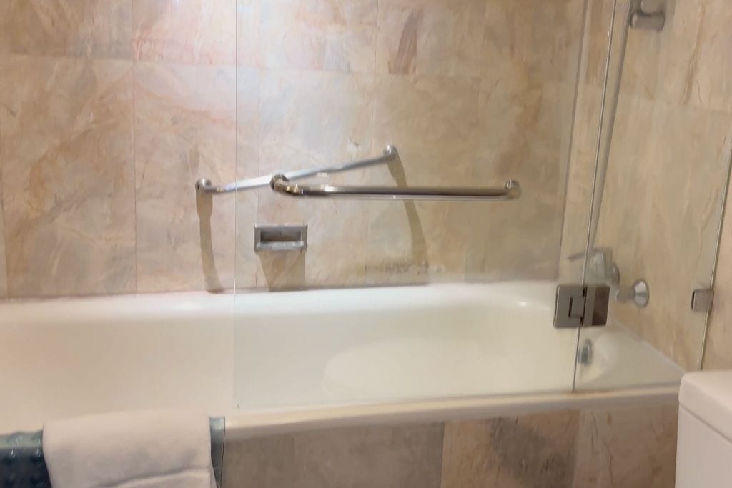 The high-sided tub in the bathroom of the hotel with the shower inside of the tub.