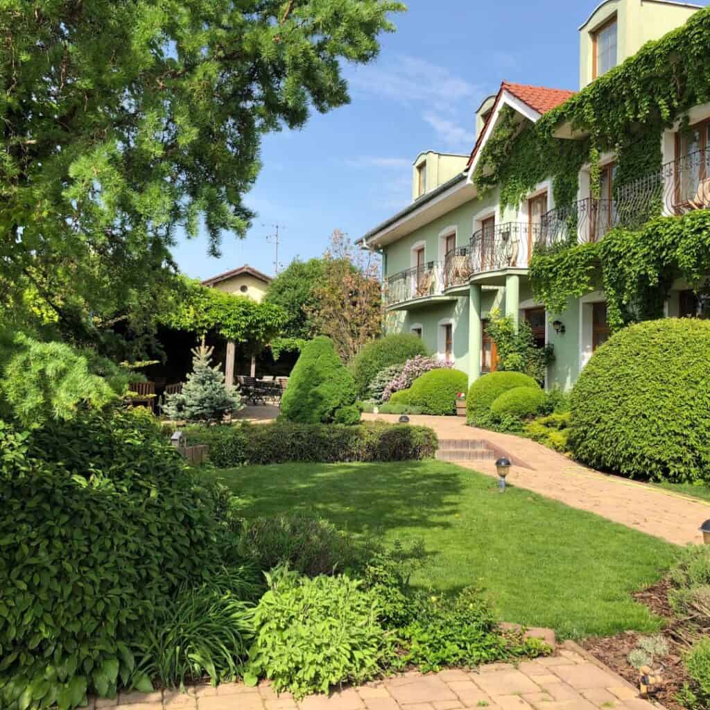 The Penzione Tematin in Slovakia, a green building nestled among beautiful green lawn and plantings.