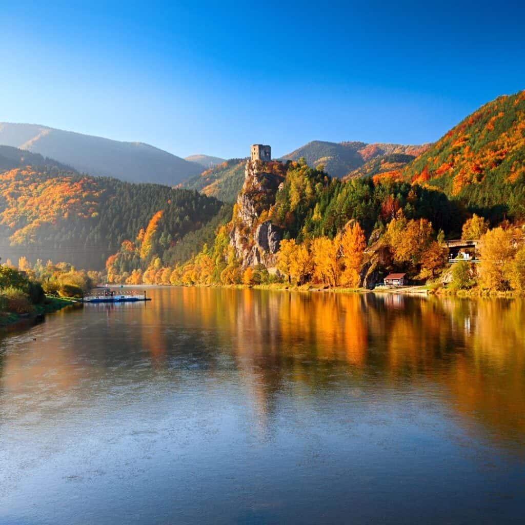 A calm lake in the Fall with mountains in the background.