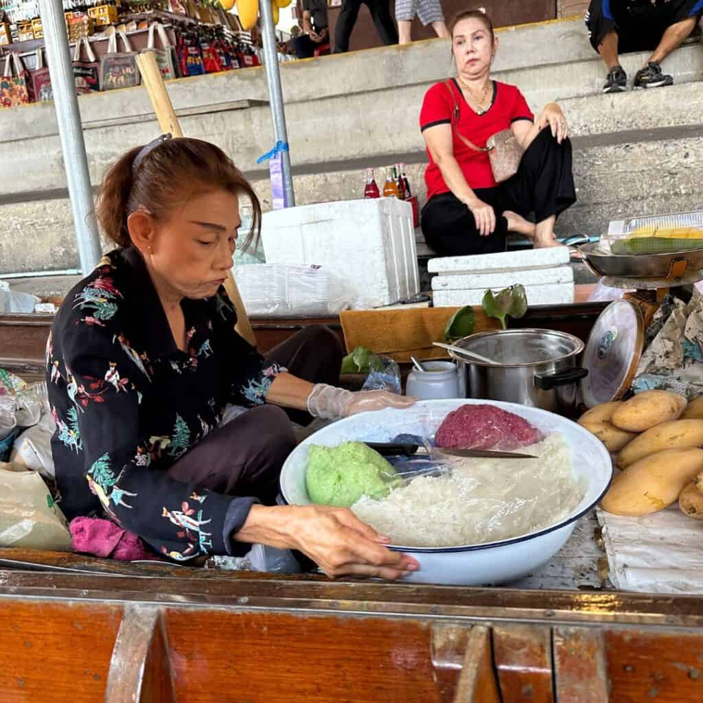 A lady preparing mango and spicy rice in a boat on the canal