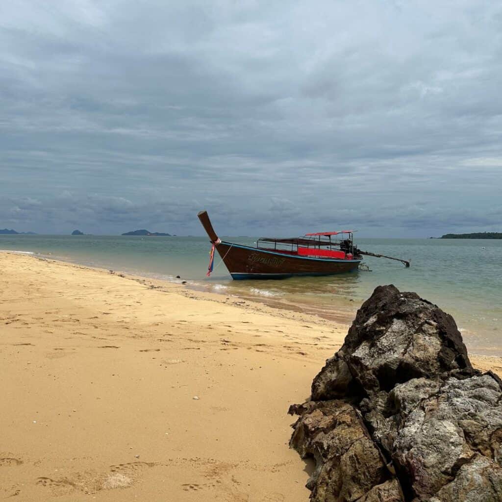 A longboat at anchor in the bay with the ocean behind it.