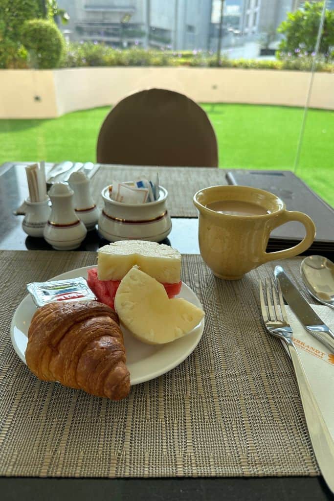 A small breakfast of croissant, fruit, and coffee in front of the swimming pool at the hotel.