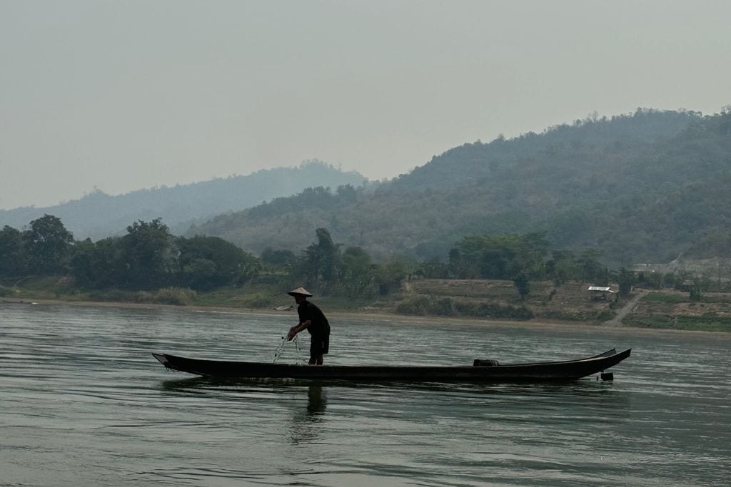 A fisherman casting his nets out on the Mekong River in Laos.