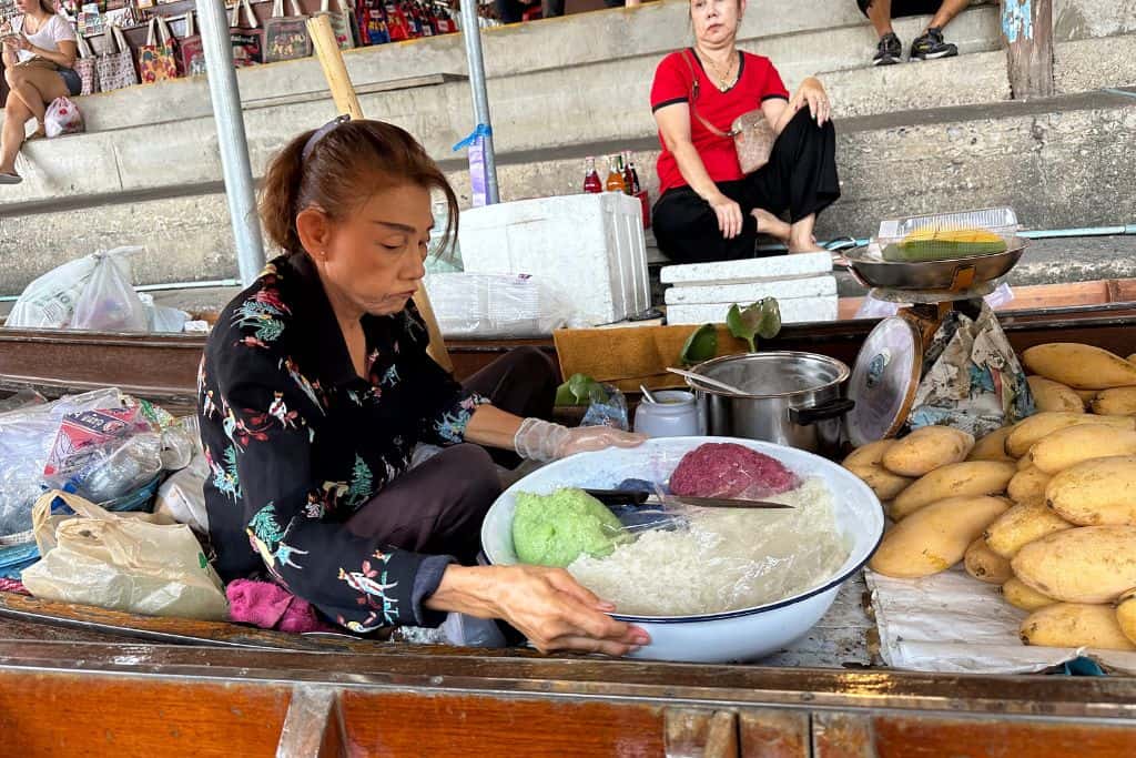 A lady preparing sticky rice and mango on the boaton the canal.