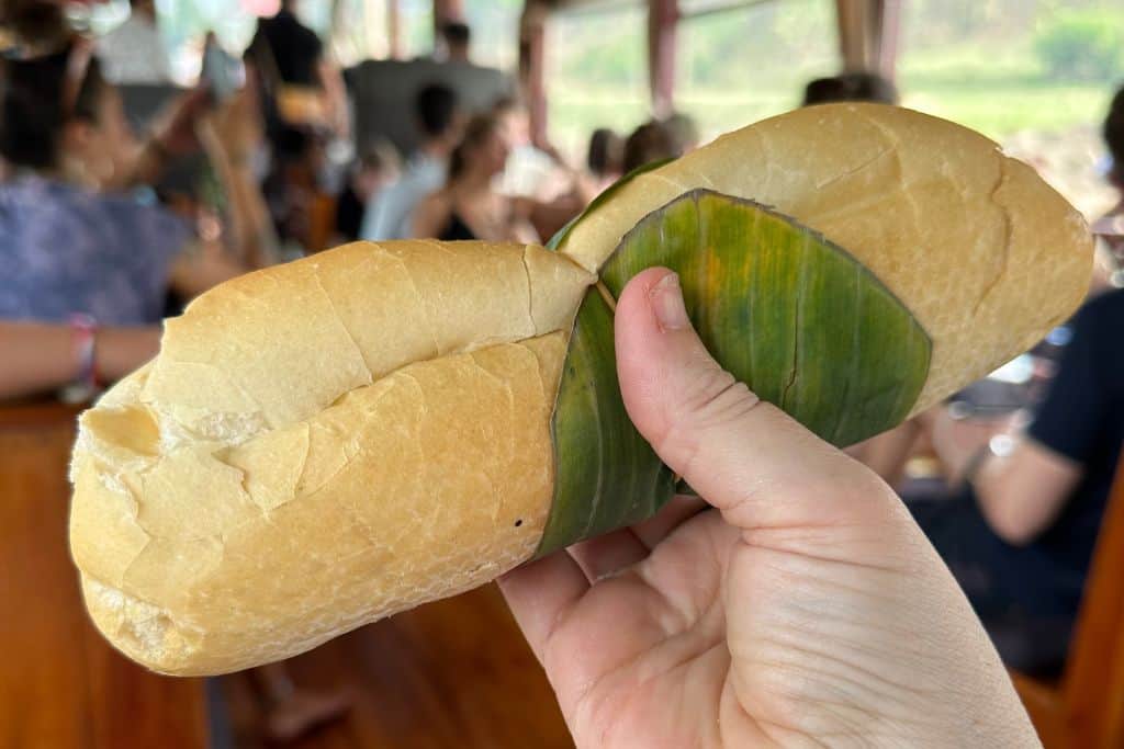 A chicken sandwich on a long bun with a leaf on the outside.