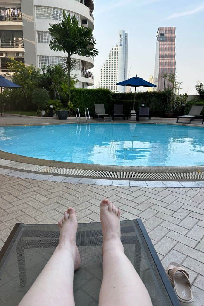 Sitting in front of the swimming pool on a lounger.