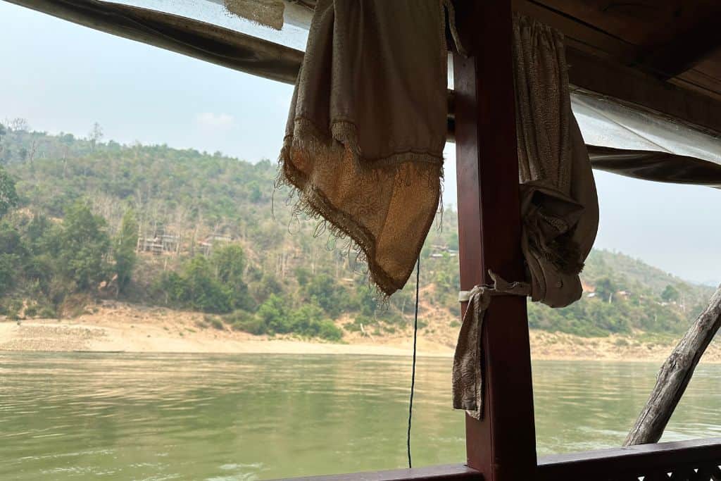 The view of the shore across the Mekong River from the window in the slowboat.