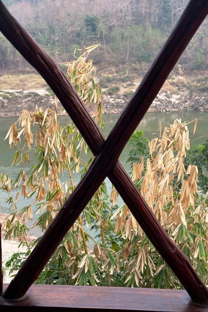 A view through the crossed railing slats across the river