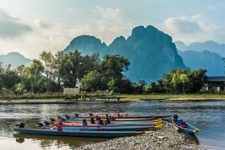 The mountains behind the river in Laos with a longboat in the foreground.