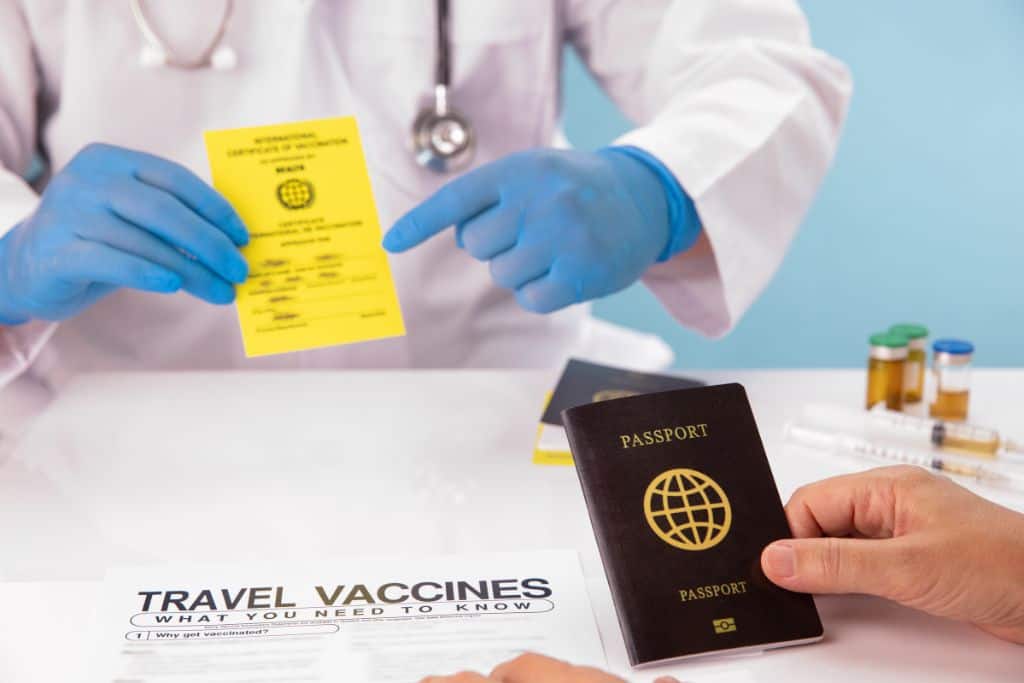 A doctor showing a vaccination card and a patient holding a passport. This is a n important tip for traveling to Laos.