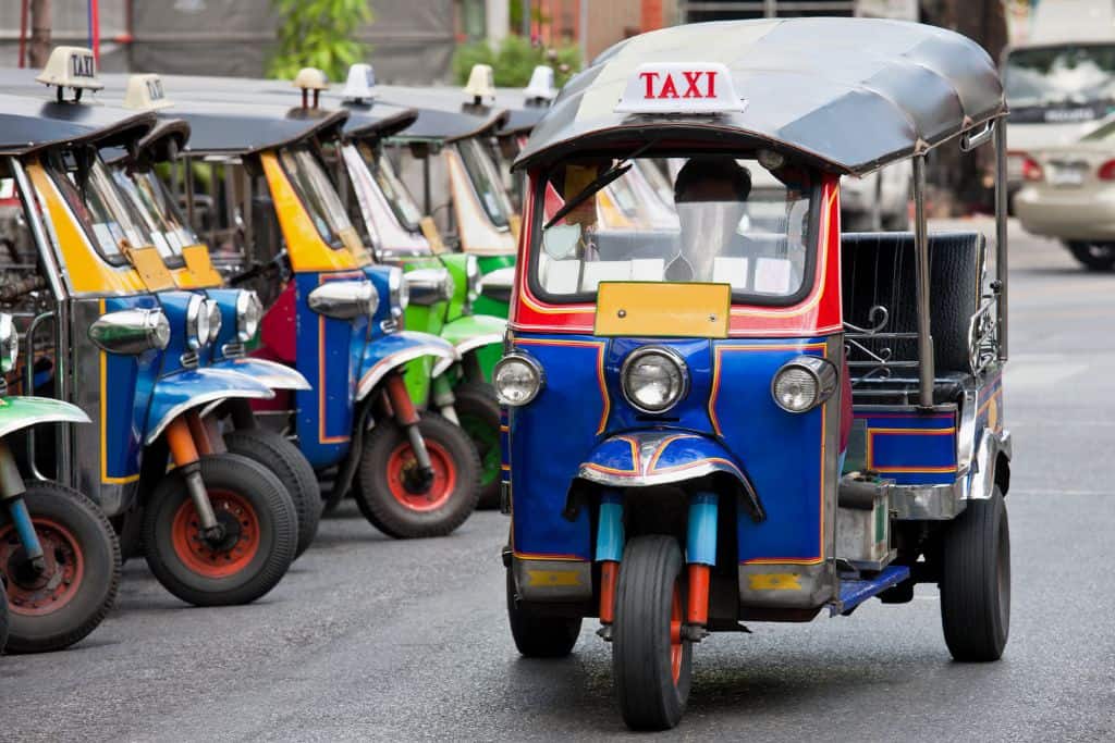 A regular sized blue tuk-tuk with a gray canvas roof and open sides.