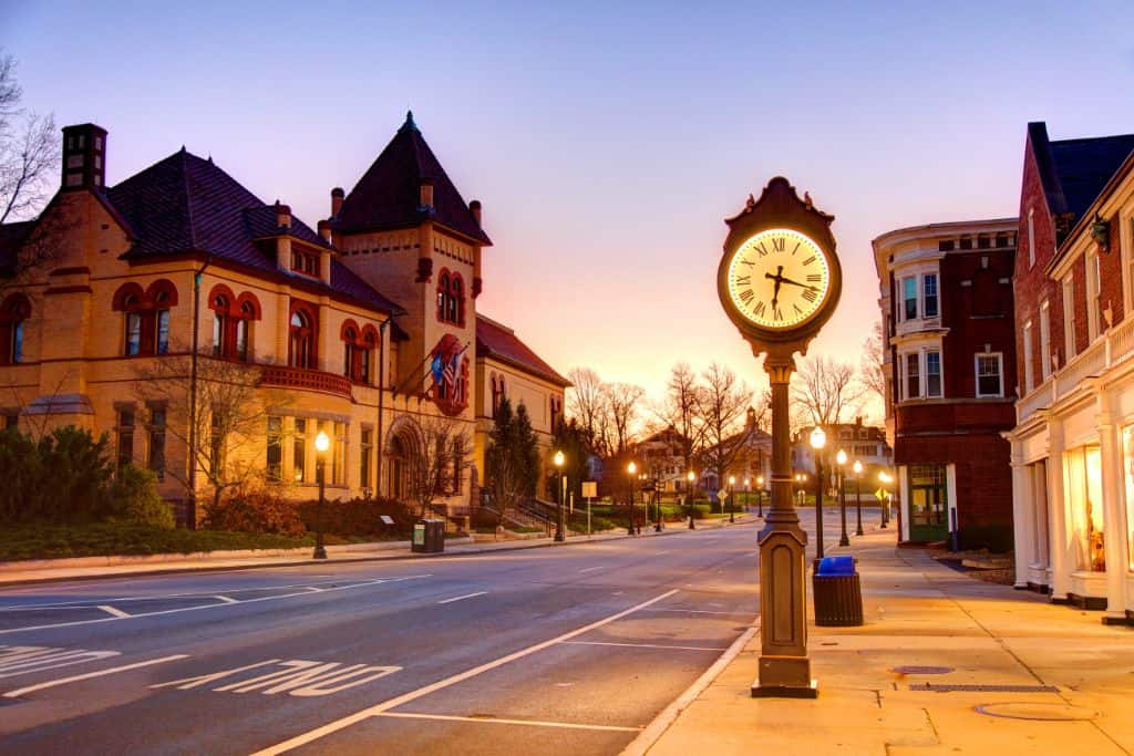 The standing clock on the street in the glow of the lights.