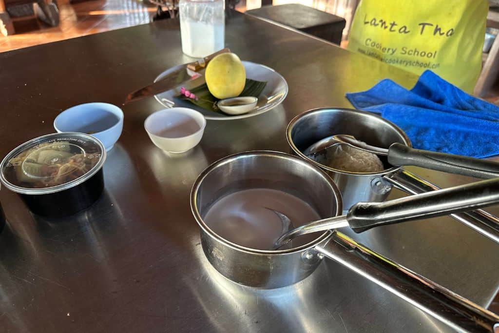 The ingredients prepped for sticky rice with a small stainless steel pan with coconut milk and the bowl of steamed rice next to it.