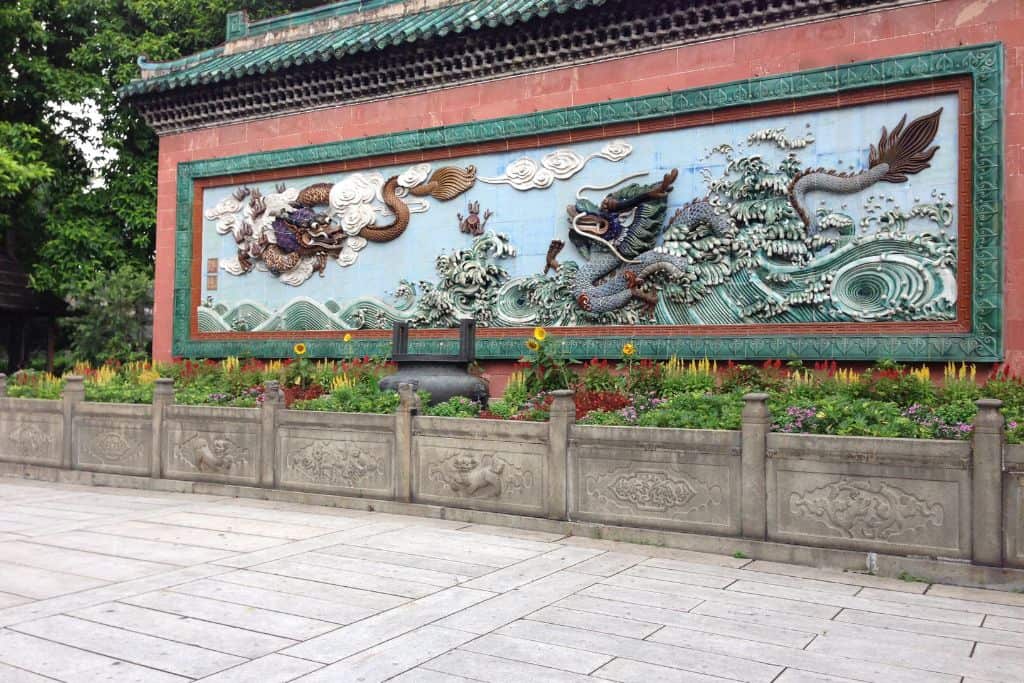 A colorful wall mural in front of a temple complex in Foshan, China.