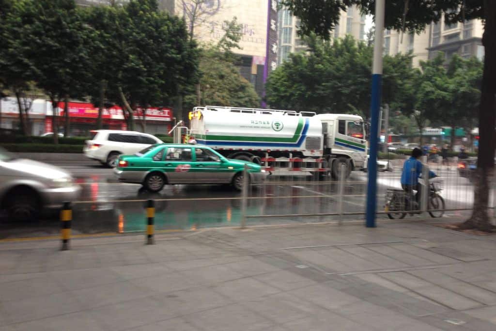 A green taxi on the busy street intersection in Guangzhou, China.