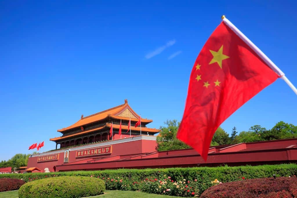 A red Chinese flag against a bright clear blue sky in Beijing.