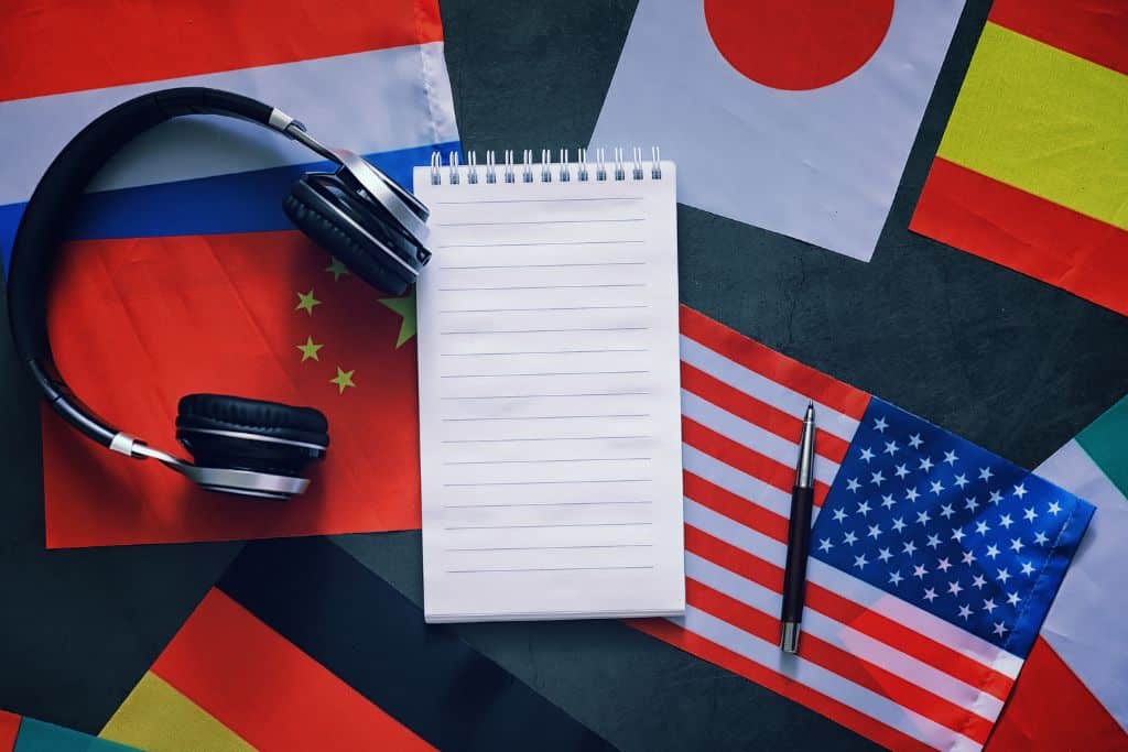 A notebook and headphones laying on top of assorted flags from other countries.