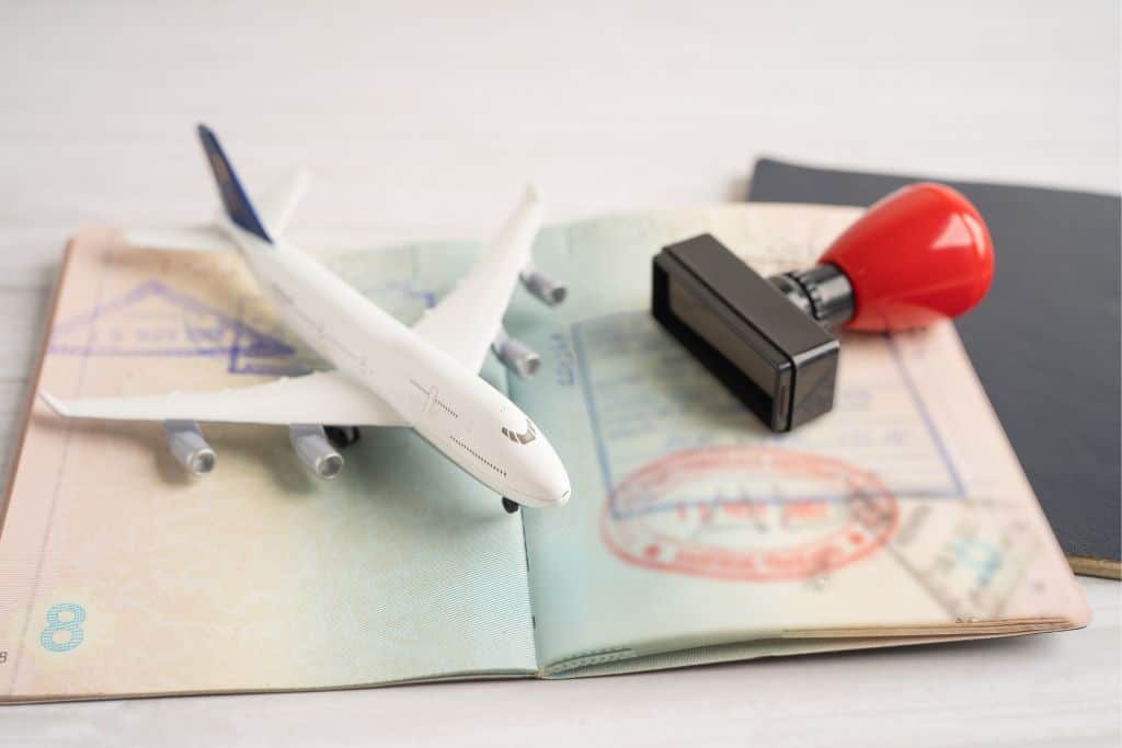 A passport with a stamp and a small toy airplane sitting on top.