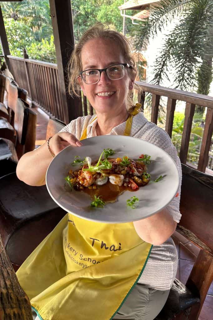 Me holding my seafood with tamarind sauce dish served on a round, white plate.