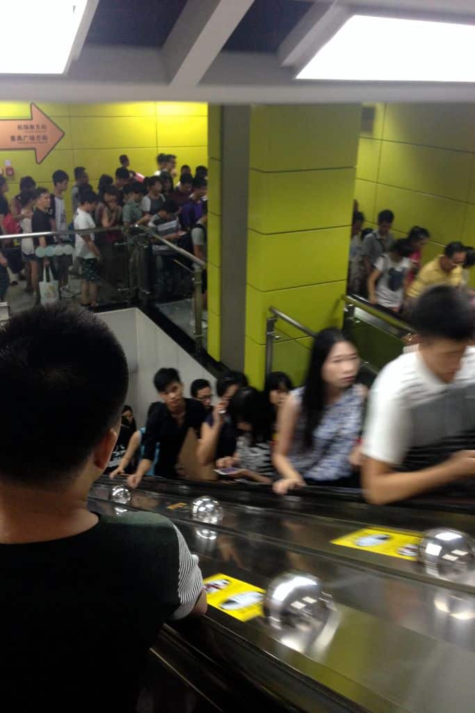 The crowded subway in Guangzhou with many people on the escalators and walkways.