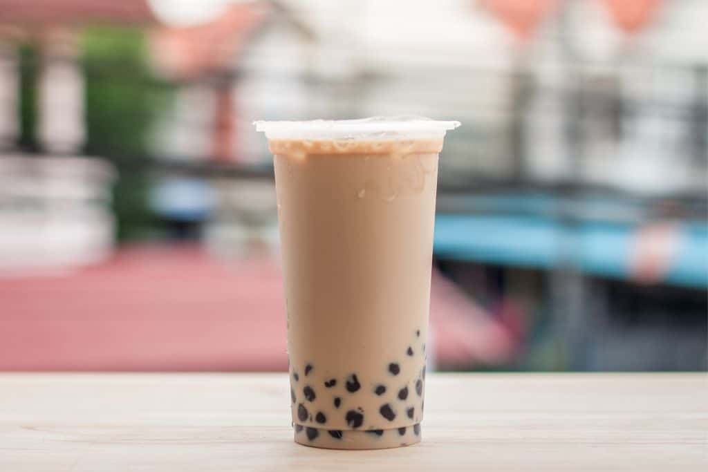 A plastic cup filled with bubble tea and with a plastic sealed lid on it.