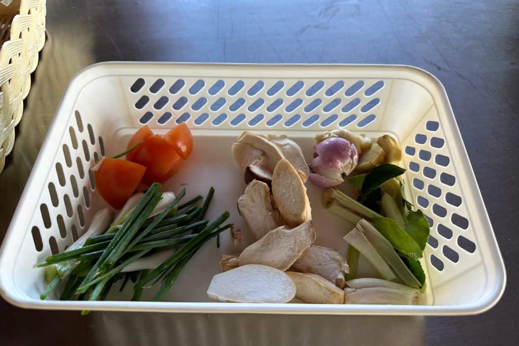 The chopped and prepped ingredients for the Tom Kha soup in a rectangular white basket.