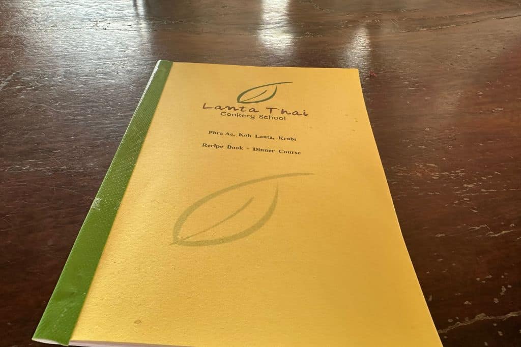 A paper copy of a yellow cookbook with the ingredients and directions for making 10 different Thai dishes.